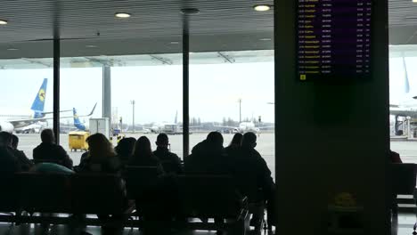 Passagiere-am-Flughafen-warten-auf-die-Einschiffung.-Passagiere-warten-auf-die-Landung-am-Flughafen.-Im-Hintergrund-ist-ein-Flugzeug.