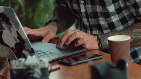 Men-hands-freelancer-working-by-laptop-computer-in-cafe-closeup