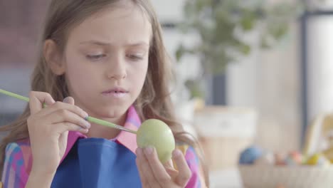 Portrait-of-cute-girl-painting-Easter-egg.