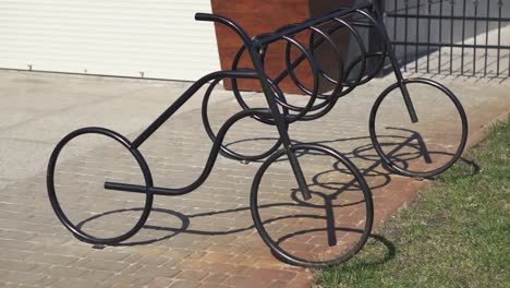 Bicycle-parking-place-in-the-city-park-on-a-sunny-summer-day.-Metal-construction-to-install-bikes-on-parking.-Close-up