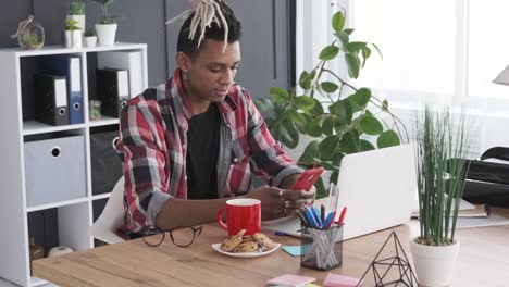 Businessman-using-mobile-phone-and-laptop-at-office-desk