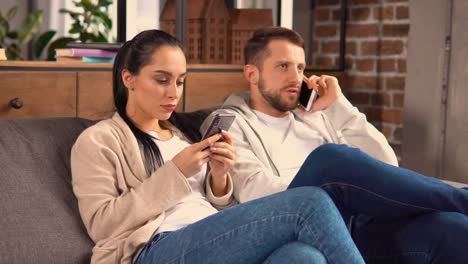 Couple-sitting-on-the-couch-while-communicating-with-friends