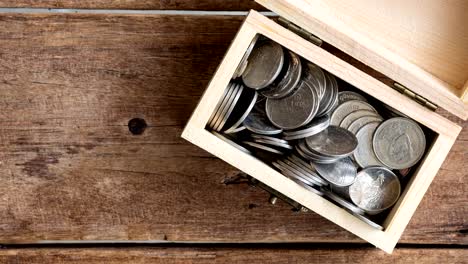 stop-motion-footage-of-silver-coins-Thai-Baht-increasing-in-toy-wooden-chest-on-wwod-table,-top-view