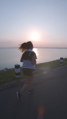 Vertikale-Videos.-Asiatische-Frauen-joggen-in-der-Straße-am-frühen-Morgen-Sonnenlicht-am-Wasserspeicher-Pa-Sak-Jolasid-Dam.-Konzept-des-Gewichtsverlustes-mit-Bewegung-für-die-Gesundheit.-Langsame-Bewegung,-Rückansicht