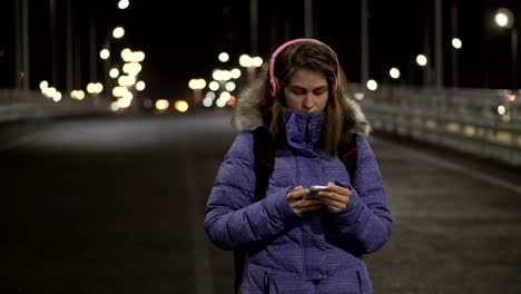 La-chica-del-teléfono-inteligente-está-en-la-ciudad-por-la-noche,-hablando-en-las-redes-sociales