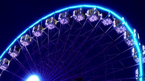 Beleuchtetes-Riesenrad-dreht-sich-gegen-einen-dunklen-Himmel.