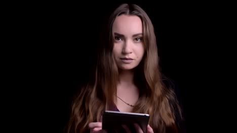 Closeup-shoot-of-young-attractive-caucasian-female-using-the-tablet-and-then-looking-aty-camera-with-background-isolated-on-black