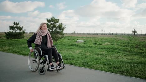 Happy-young-woman-is-whirling-her-body-in-wheelchair-in-park-area-in-sunny-day