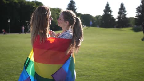 Young-gay-couple-standing-wrapped-in-lgbt-flag