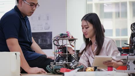 Female-electronics-engineer-working-with-robot-project-at-lab-with-friend.-Technology-and-innovation-concept.