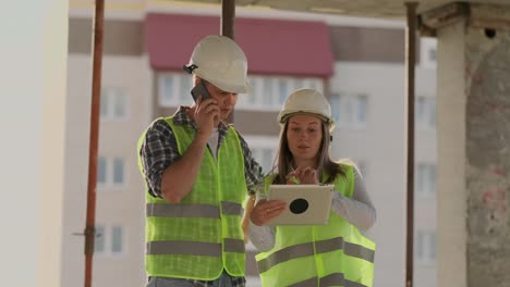 Supervisor-of-a-building-under-construction-man-discussing-with-engineer-designer-woman-the-progress-of-construction-and-examines-a-building-plan