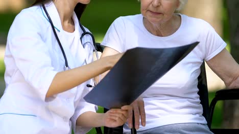 Vertebrologist-explaining-to-disabled-patient-problems-with-her-spine-on-x-ray