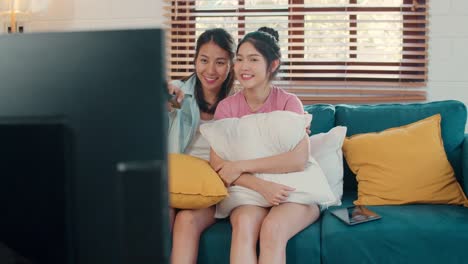 Junge-asiatische-lesbische-Paar-fernsehen-zusammen,-während-liegen-Sofa-im-Wohnzimmer-zu-Hause.