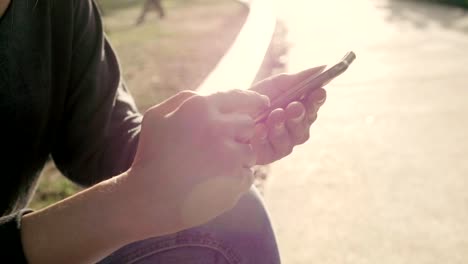 Mujer-usar-el-teléfono-móvil-y-sentarse-en-el-parque-con-efecto-de-luz-solar