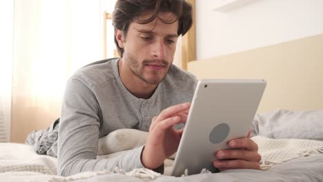 Man-using-digital-tablet-on-bed-at-home