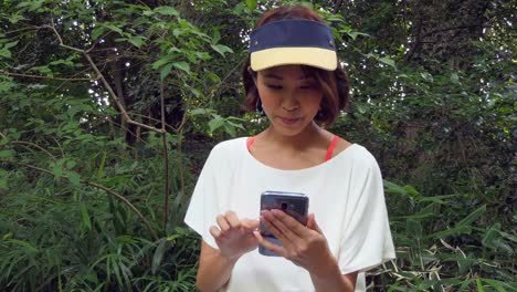 Cheerful-Woman-Typing-On-Mobile-Phone-After-Running-In-Park