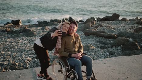 Cheerful-girl-and-handicapped-boyfriend-taking-selfie-outdoors