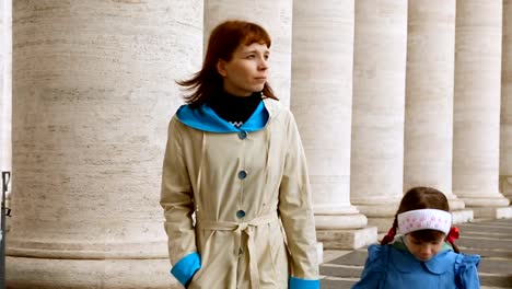 Woman-with-her-daughter-walking-between-columns-on-Piazza-San-Pietro,-Vatican