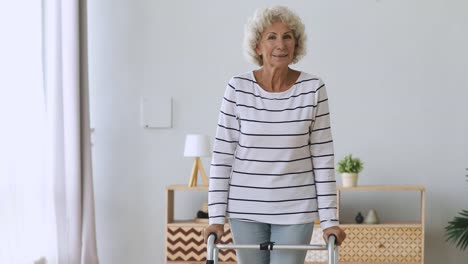 Happy-disabled-senior-woman-stand-hold-walker-looking-at-camera