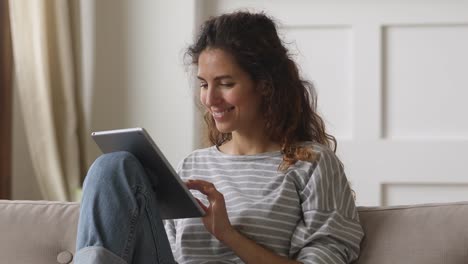 Glückliche-junge-Frau-entspannen-zu-Hause-auf-dem-Sofa-mit-Tablet