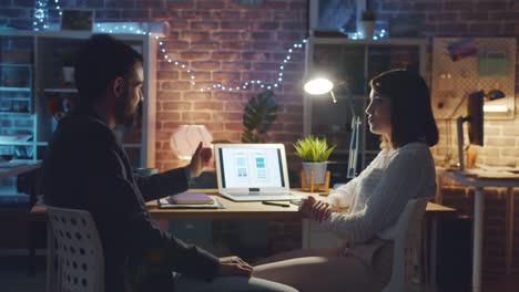 Creative-people-discussing-smartphone-app-interface-working-with-laptop-in-office