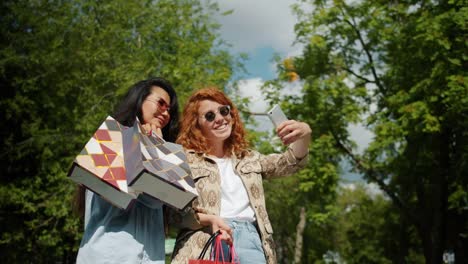 Porträt-glücklicher-Studentinnen,-die-im-Park-Selfies-mit-Einkaufstaschen-machen