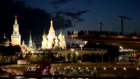 Schwimmende-Brücke-von-Zaryadye-Park-auf-Moskvoretskaya-Embankment-des-Flusses-Moskva-(und-touristisches-Vergnügungsboot)-bei-Nacht.-Moskau,-Russland.