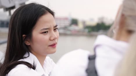 Asian-lesbian-couple-talking-while-standing-on-the-bridge.