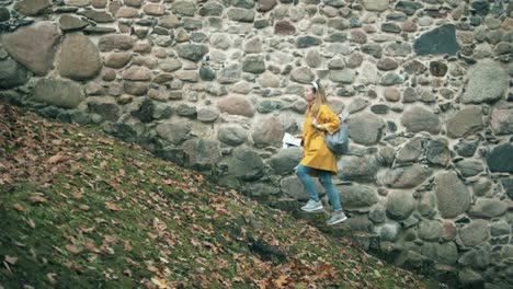 Eine-Frau-mit-einer-Karte-geht-die-Treppe-entlang-einer-alten-Mauer