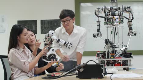 Asian-teenage-engineer-assembling-and-testing-robotics-responses-in-laboratory.-Architects-design-circuit-meeting-share-technology-ideas-and-collaborating-development-robot.