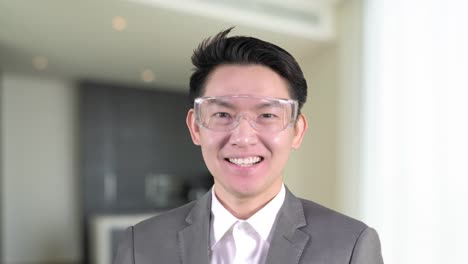 Asian-business-man-smiling-wear-smart-glasses-Iot-internet-of-thing-home-interior-blur-background,-business-work-from-home-concept