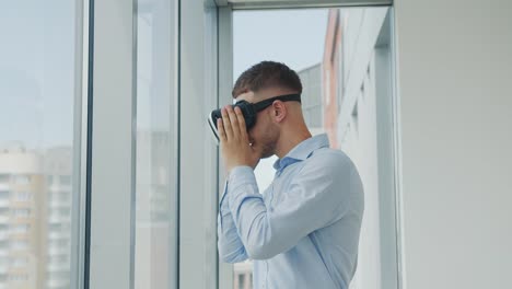 Close-up-Young-man-sitting-at-a-desk-in-the-office-uses-augmented-reality-glasses-to-work-on-business-projects-in-various-fields.-Work-in-Virtual-Reality