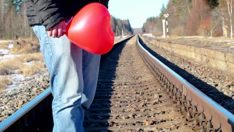 Mann-mit-roten-herzförmigen-Ballon-auf-der-Bahn