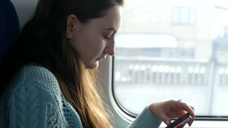 Junges-Mädchen-Reisen-in-einem-Zug-und-Mobiltelefon-zu-benutzen.-Schöne-Frau-sendet-eine-Nachricht-vom-Smartphone.-Attraktives-Mädchen-mit-Freunden-chatten.