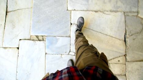 Top-view-POV-of-man-in-sneakers-walking-historical-ancient-sidewalk