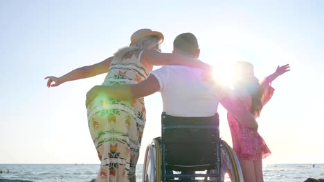 personas-con-discapacidad-abraza-a-mujer-y-su-hija,-no-válida-con-la-mujer-embarazada-y-el-niño-en-el-mar-de-fondo,-familia-feliz