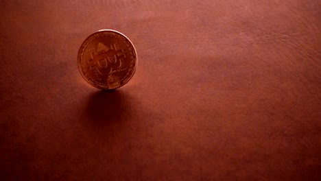 bit-coin--spinning-in-slow-motion-on-leather-top-table-background