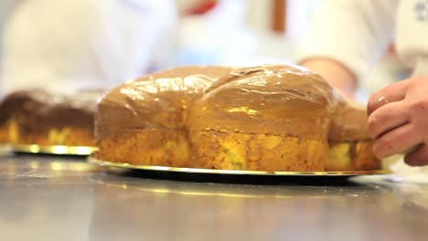 manos-de-chef-de-pastelería-decorar-Pascua-pasta-de-tortas-de-pan-dulce-con-azúcar-de-fondants,-closeup-en-la-encimera-en-confitería