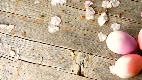 Easter-eggs-panning,-old-wooden-table-and-almond-blossom-petals