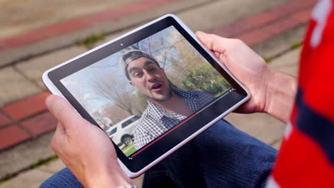 Man-Watches-a-Viral-Video-Vlogger-Outside-on-Tablet-PC