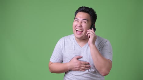 Young-handsome-overweight-Asian-man-against-green-background