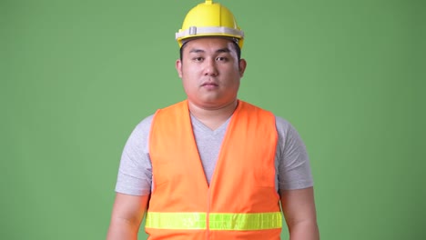 Trabajador-de-la-construcción-del-joven-guapo-asiáticos-con-sobrepeso-sobre-fondo-verde