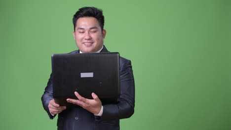 Young-handsome-overweight-Asian-businessman-against-green-background