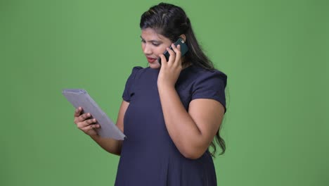 Young-overweight-beautiful-Indian-businesswoman-against-green-background