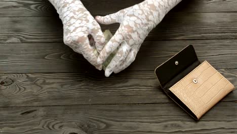 Woman's-hands,-in-white-lace-gloves,-count-the-US-dollars-banknotes.