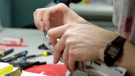 Young-engineer-is-working-with-mechanical-hand-prosthesis-in-workspace-in-company