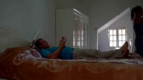 Un-hombre-y-una-mujer-se-encuentran-en-el-dormitorio-de-una-cama-y-utilizan-el-tablet-pc.-Mujer-se-levanta-y-deja