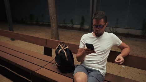 Mann,-der-eine-Smartphone-in-der-Nacht-hält.