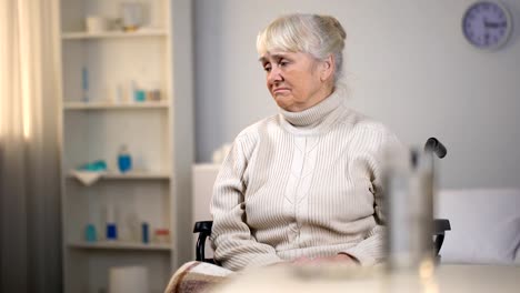 Upset-elderly-woman-in-wheelchair-thinking-about-fatal-diagnosis,-hospital-care