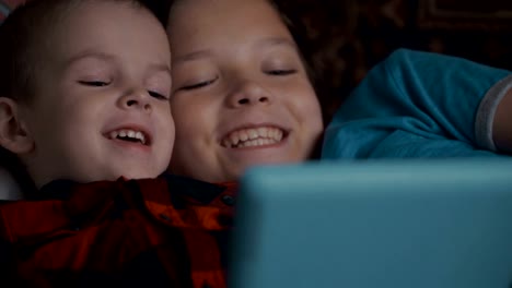 Footage-two-boys-using-tablet-pc-lying-on-sofa.